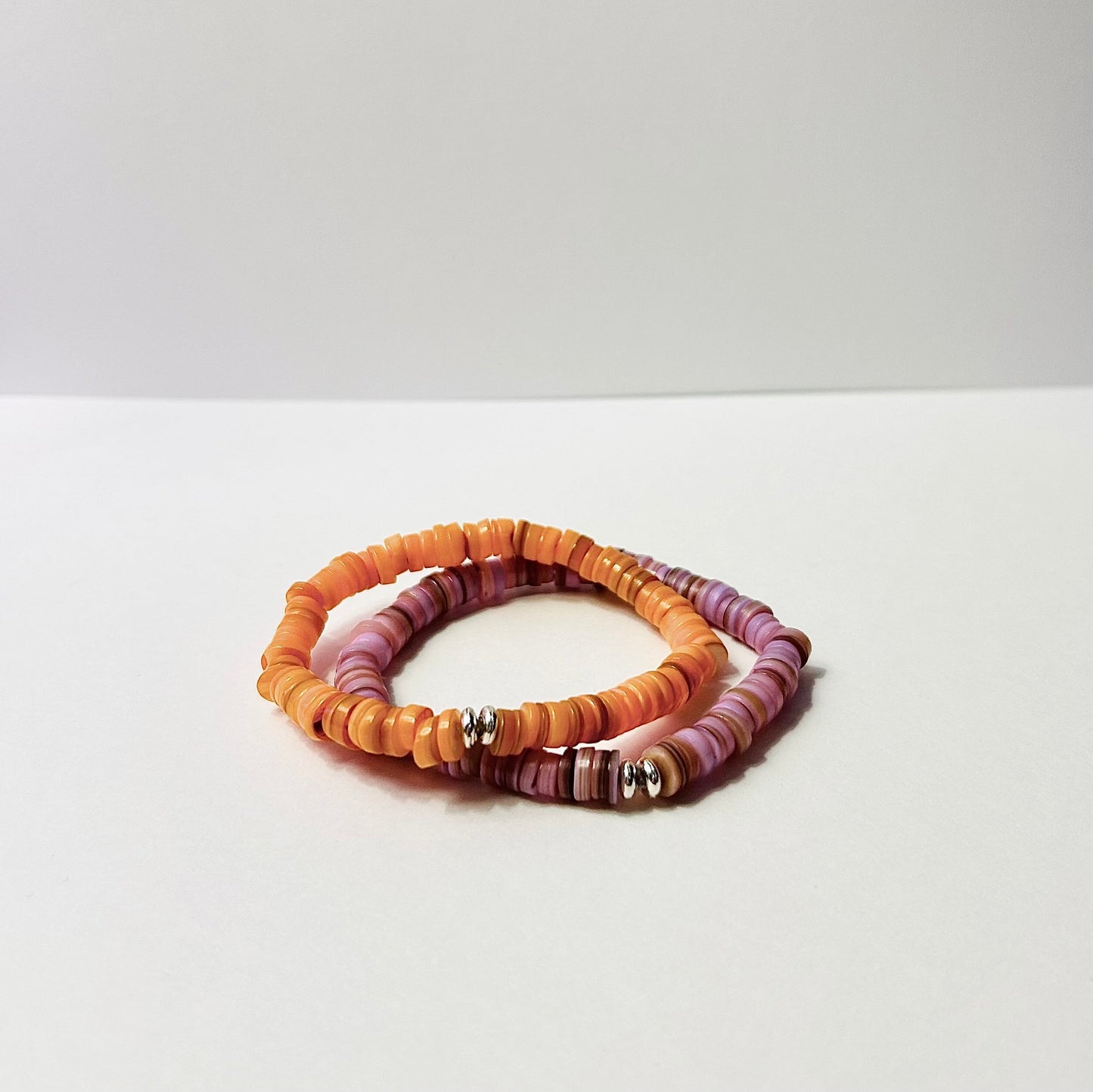 Two beaded bracelets on a white surface with a light gray background