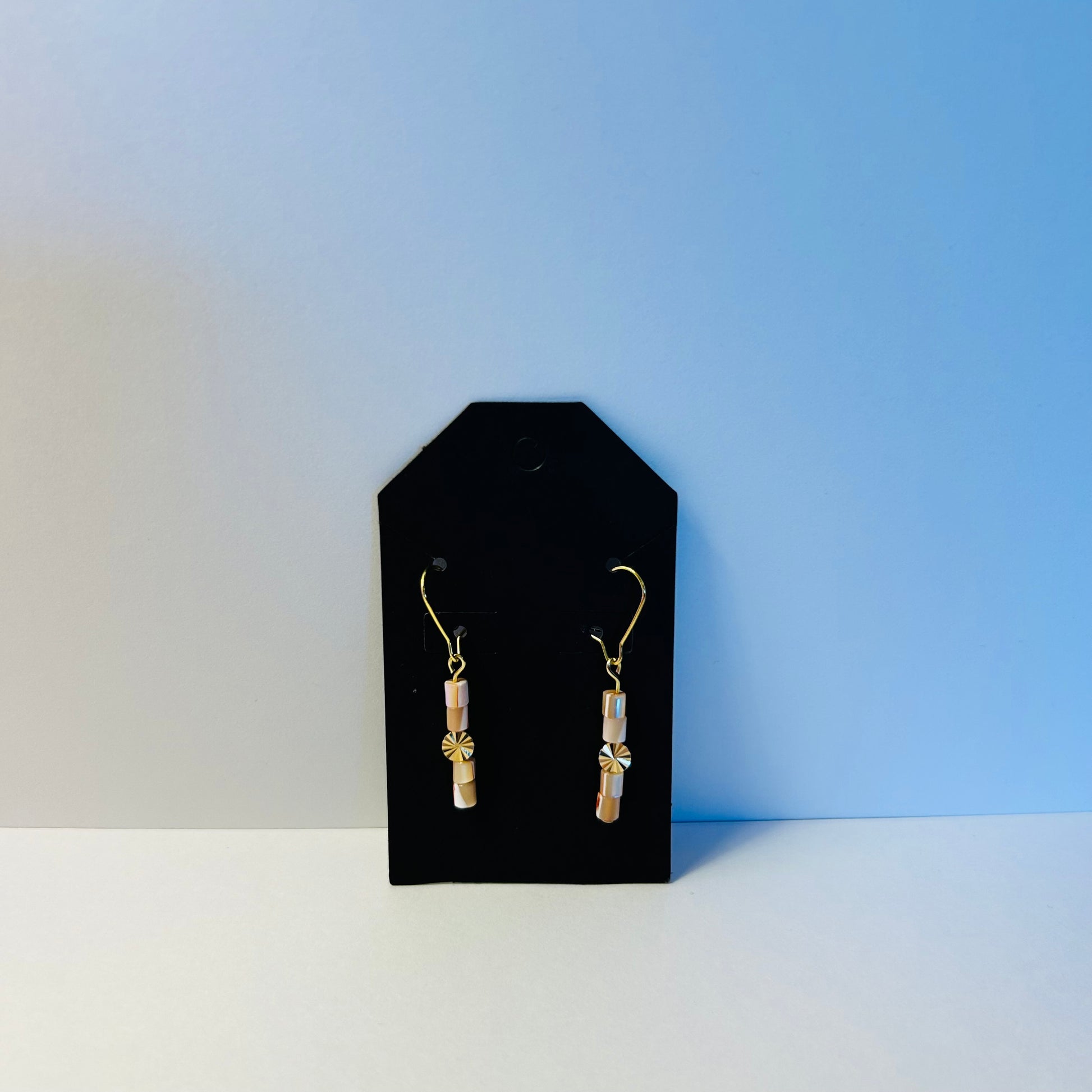 Pair of earrings on a black card against a blue background